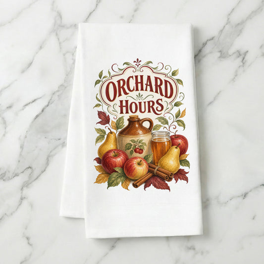 Orchard Hours Apple Cider Tea Towel folded on white marble, with apples, pears, cider jug and glass, cinnamon sticks, leaves, and vintage lettering clearly shown.