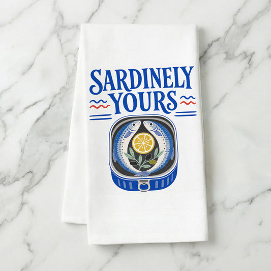 Sardinely Yours sardine and lemon tea towel styled on a marble surface.