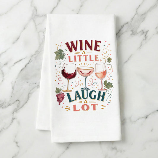 Wine a Little, Laugh a Lot tea towel styled on a marble surface.