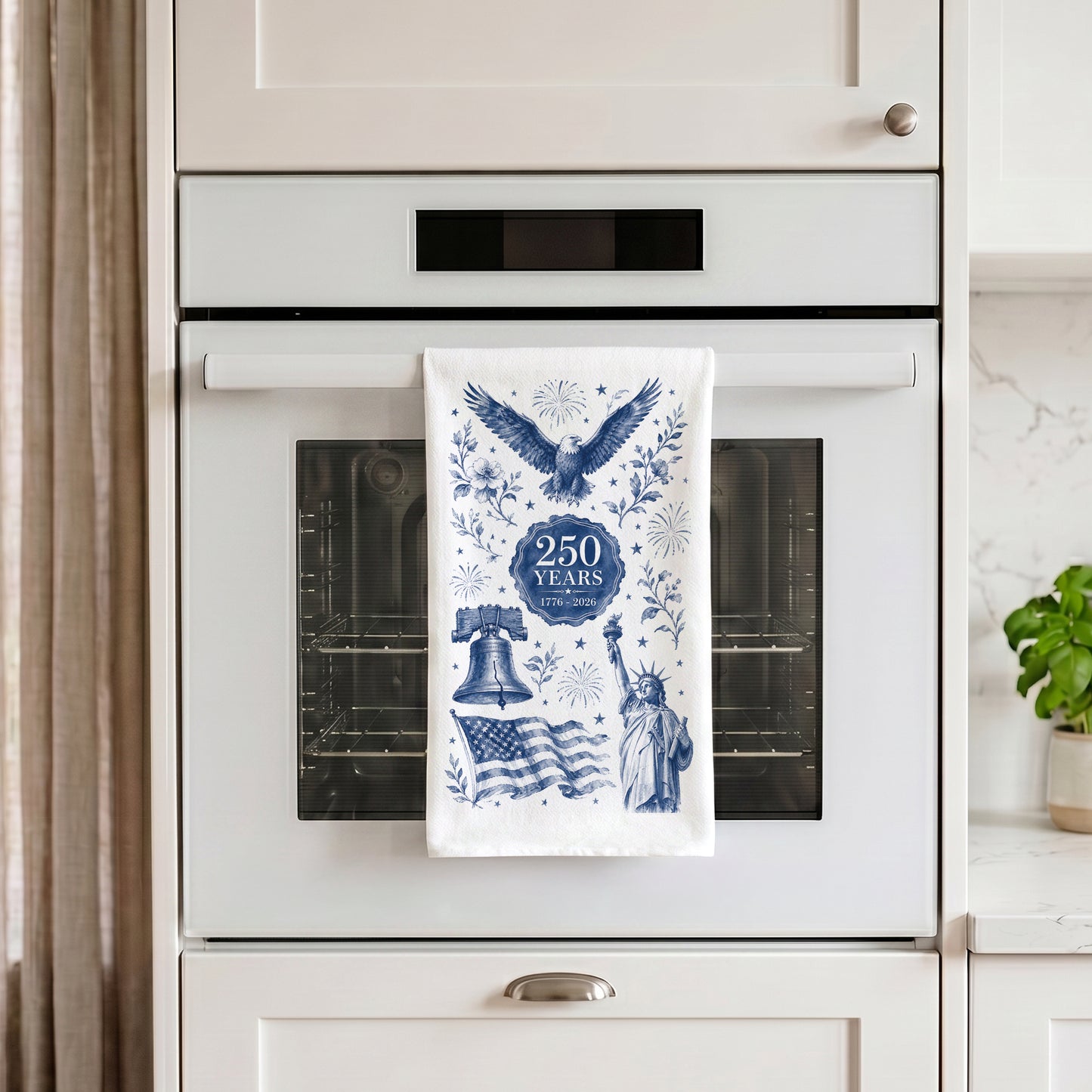 America 250th anniversary tea towel in navy toile hanging on a white oven handle in a bright modern kitchen