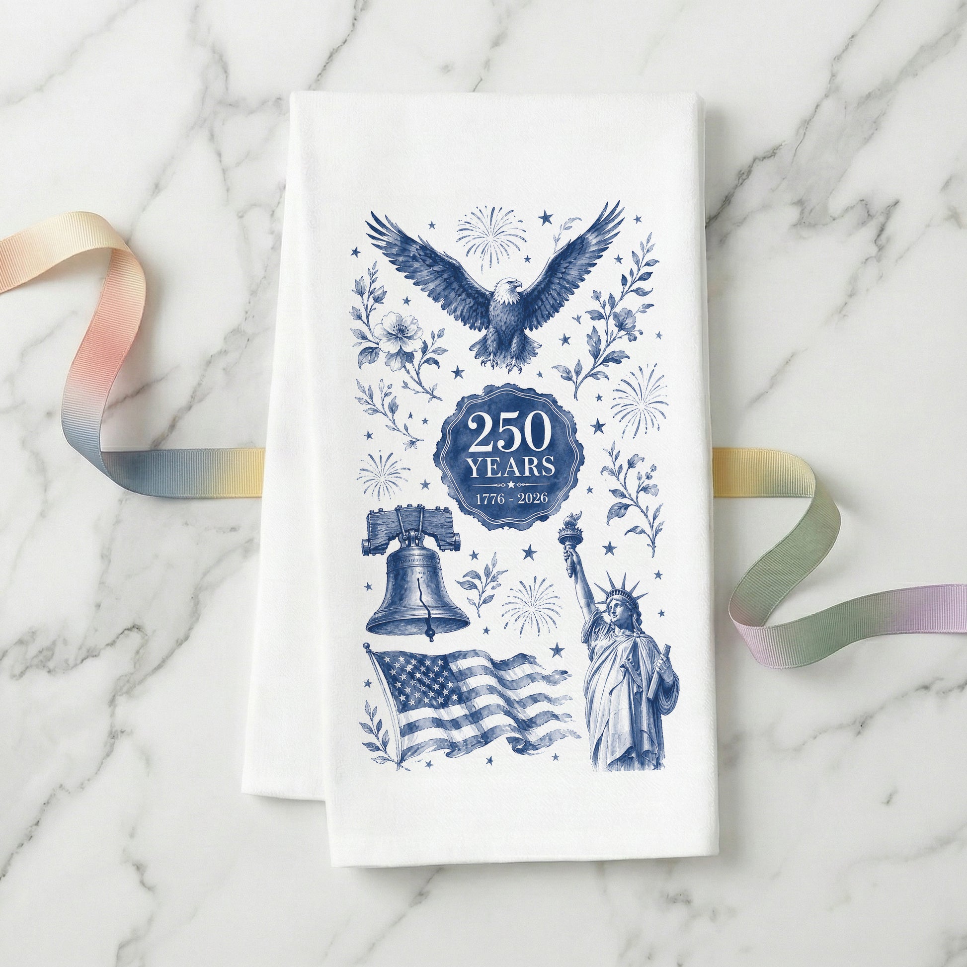 Navy toile America 250th anniversary tea towel on white flour sack organic cotton, folded on marble, with eagle, Liberty Bell, Statue of Liberty, flag and a 250 Years 1776-2026 seal