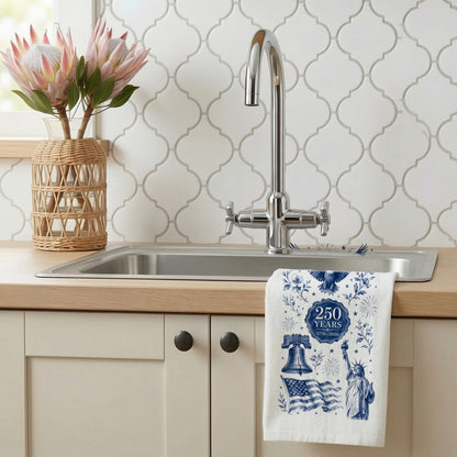Navy toile America 250th anniversary tea towel hanging at a kitchen sink beside flowers and patterned tile