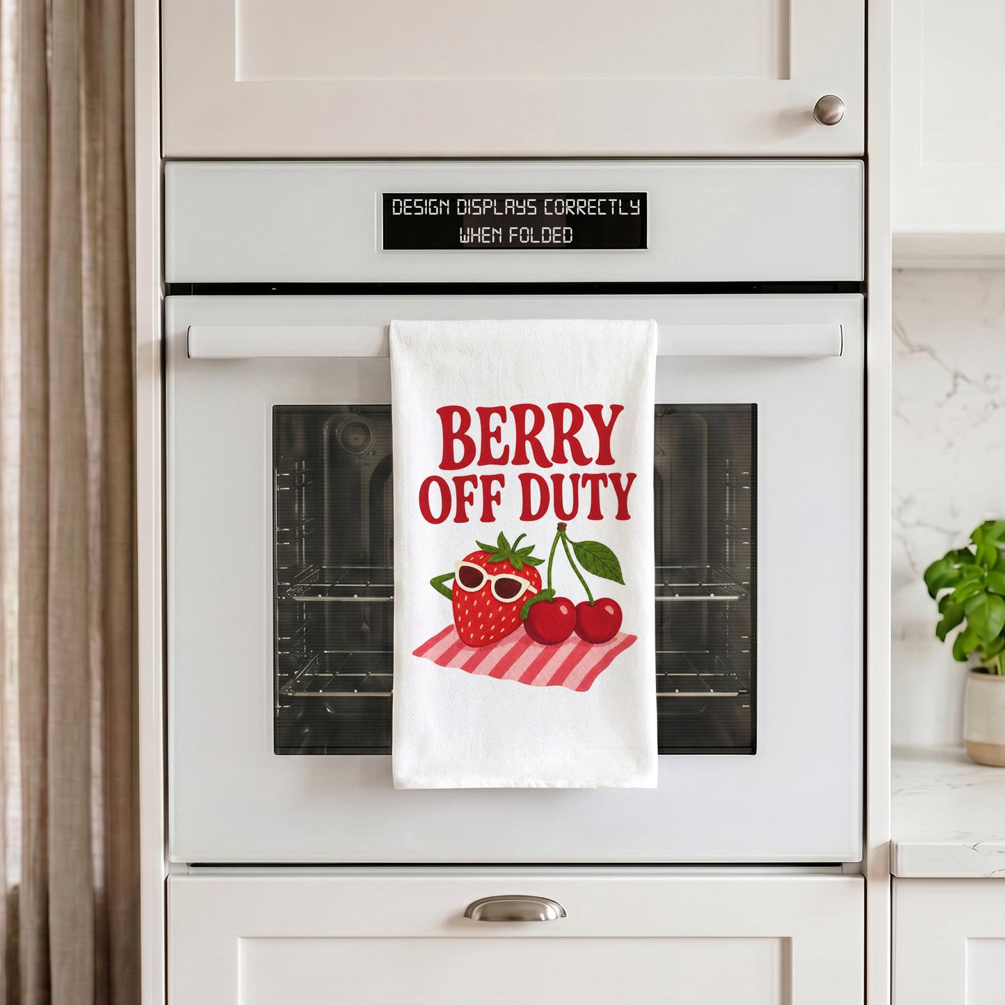 White Berry Off Duty tea towel draped over an oven handle in a kitchen setting.