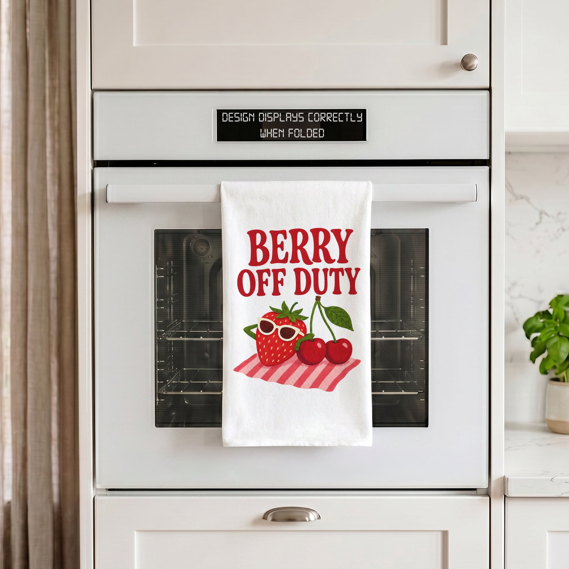 White Berry Off Duty tea towel draped over an oven handle in a kitchen setting.