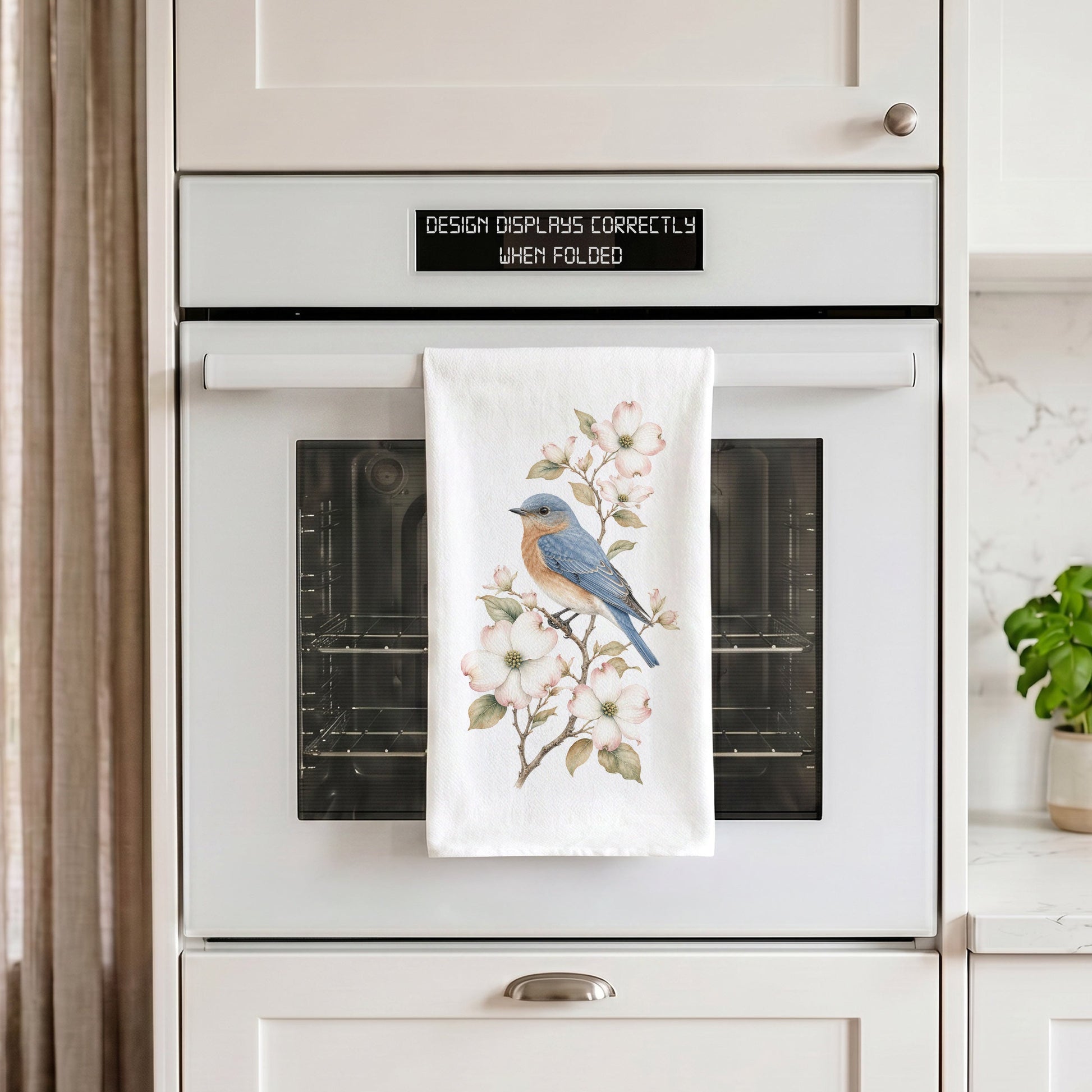 Bluebird and dogwood tea towel styled on an oven handle