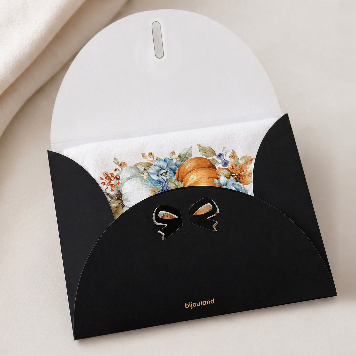 Bluebird Pumpkin tea towel tucked inside Bijouland’s black gift envelope with a gold logo.