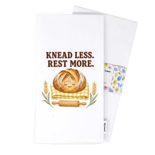 Folded Knead Less Rest More tea towel presented with its paper belly band.