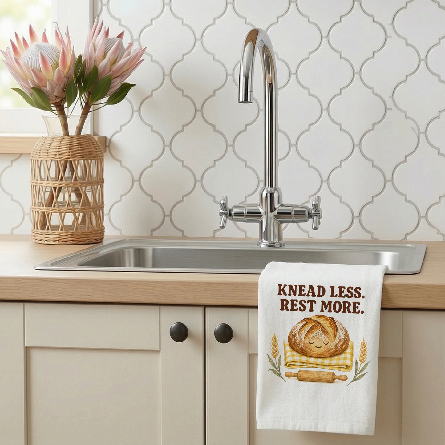 Knead Less Rest More tea towel styled beside a kitchen sink with the bread design visible.