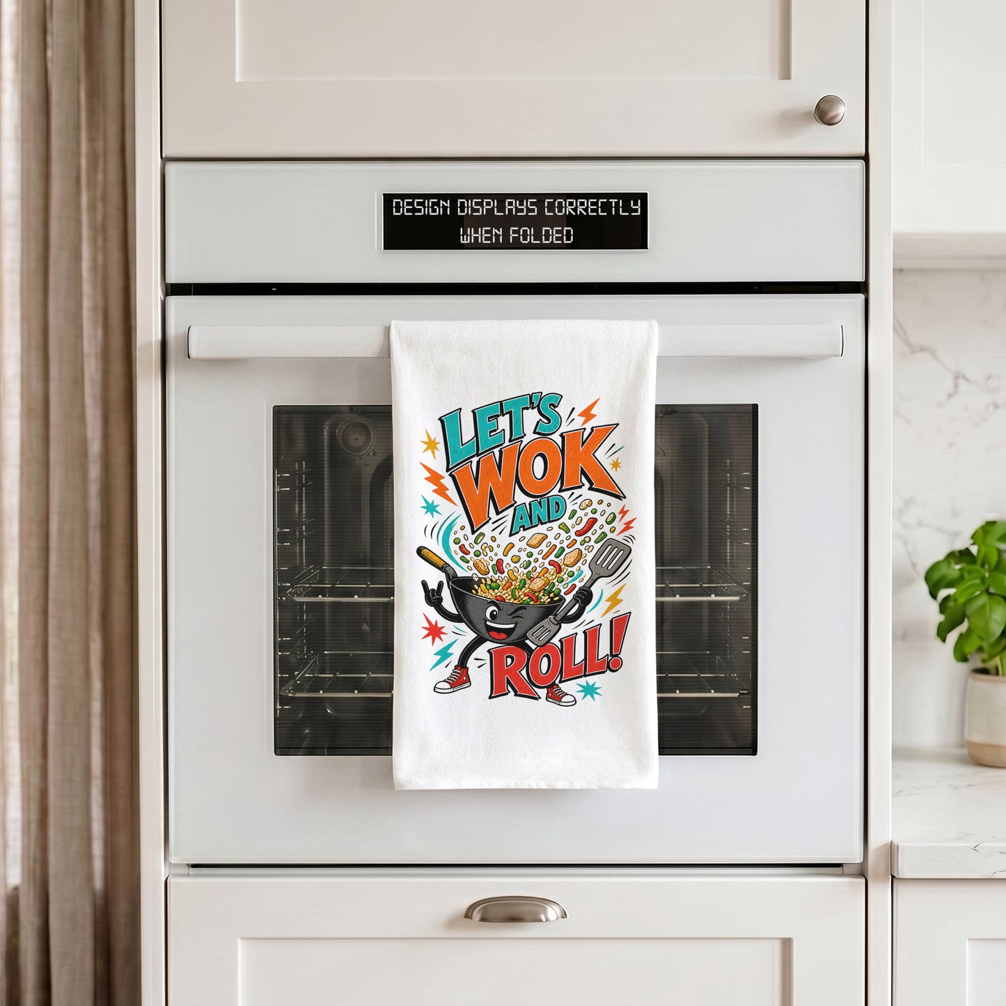 White Let's Wok and Roll funny wok cooking pun kitchen towel draped over an oven handle.