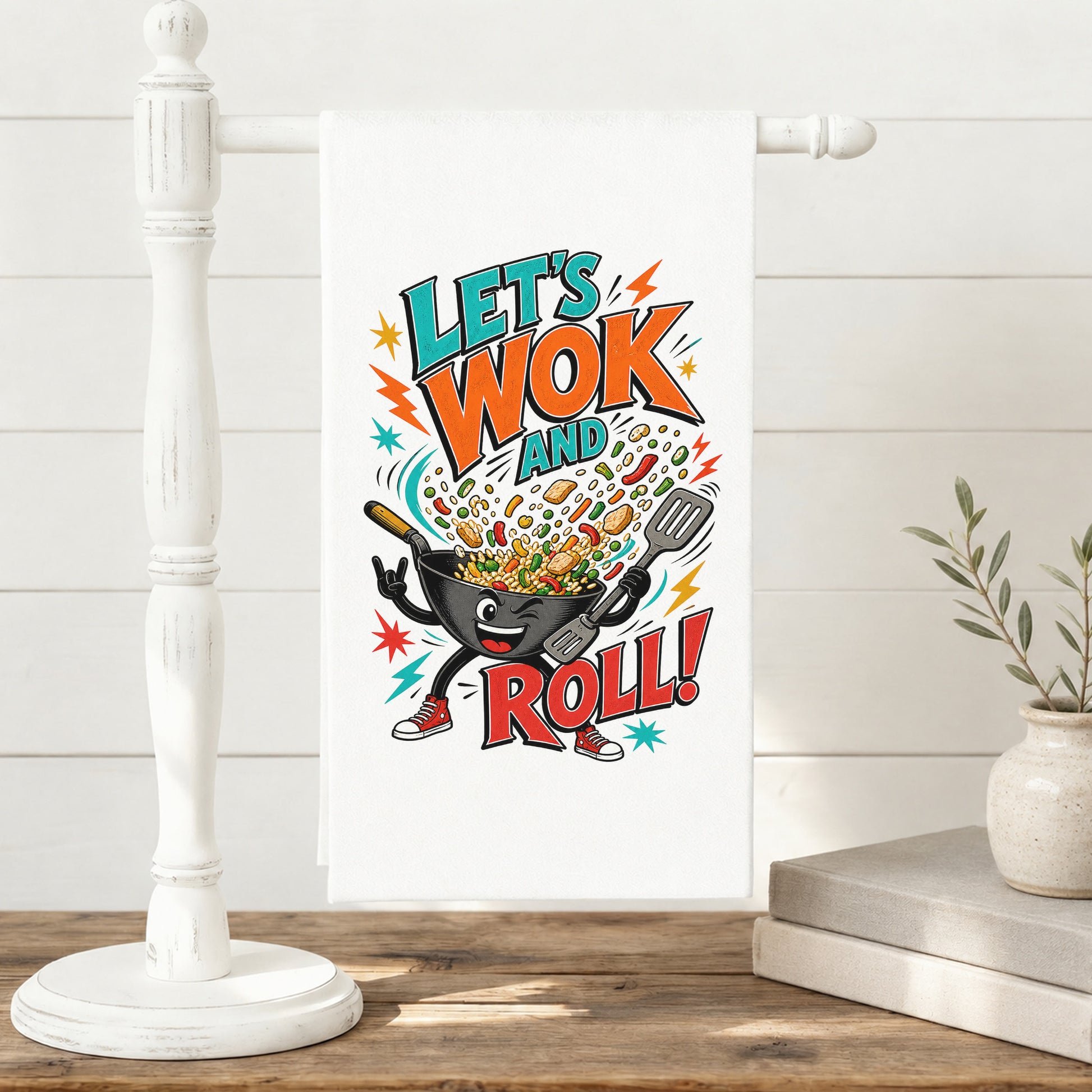 Let's Wok and Roll funny wok cooking pun tea towel displayed on a freestanding towel stand.