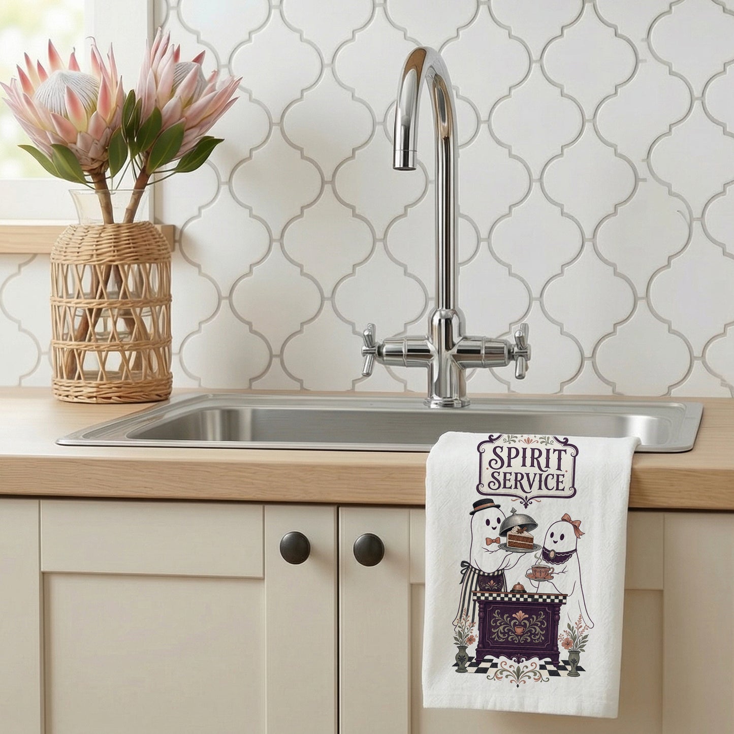 Spirit Service Ghost Halloween Kitchen Towel styled beside a bright kitchen sink, with two friendly ghosts serving cake and tea at a vintage cafe counter shown.