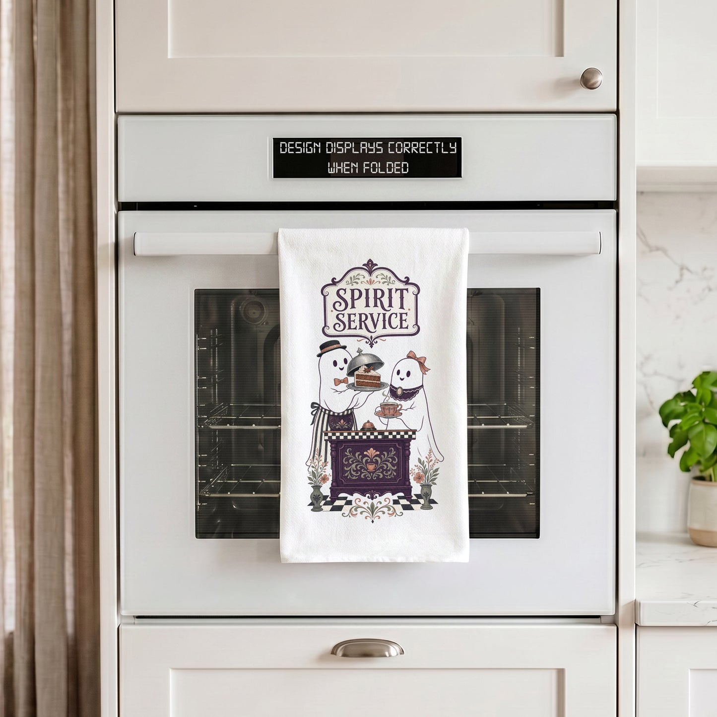 Spirit Service Ghost Halloween Kitchen Towel draped over an oven handle, with the artwork centered when folded.