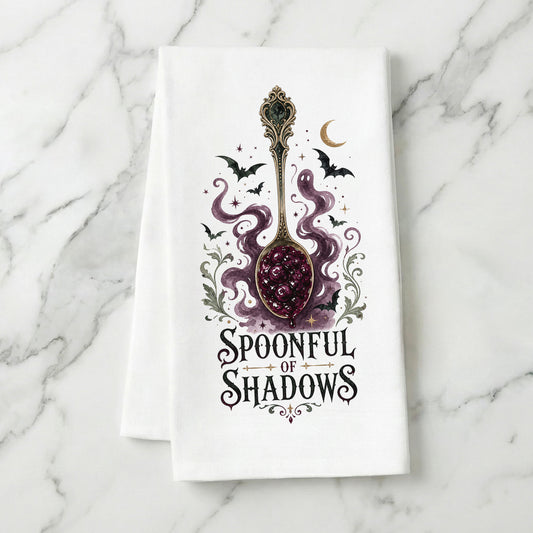 Spoonful of Shadows Gothic Halloween Kitchen Towel folded on white marble, with ornate spoon, berry jam, curling ghost shapes, bats, and crescent moon clearly shown.